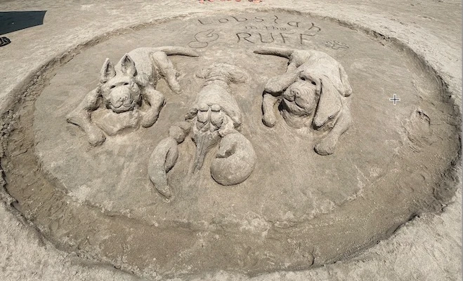 A sand sculpture of a lobster and two dogs.
