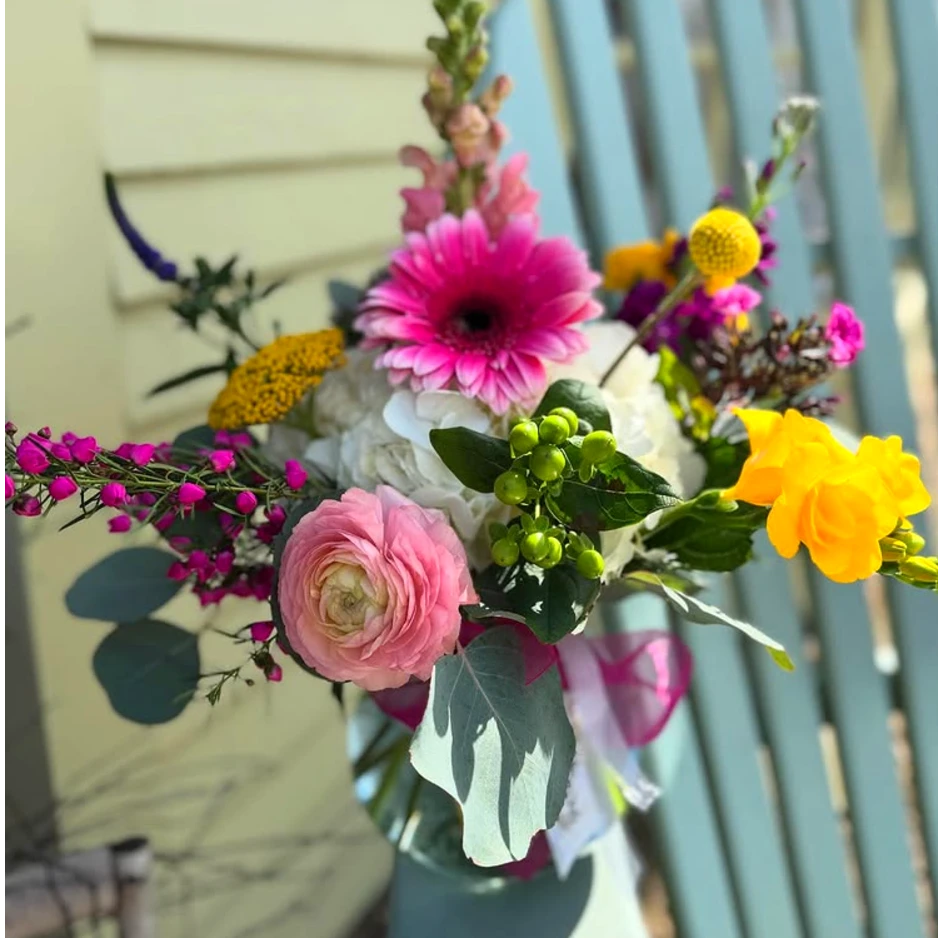 A bouquet of pink, yellow and white flowers in a vase.