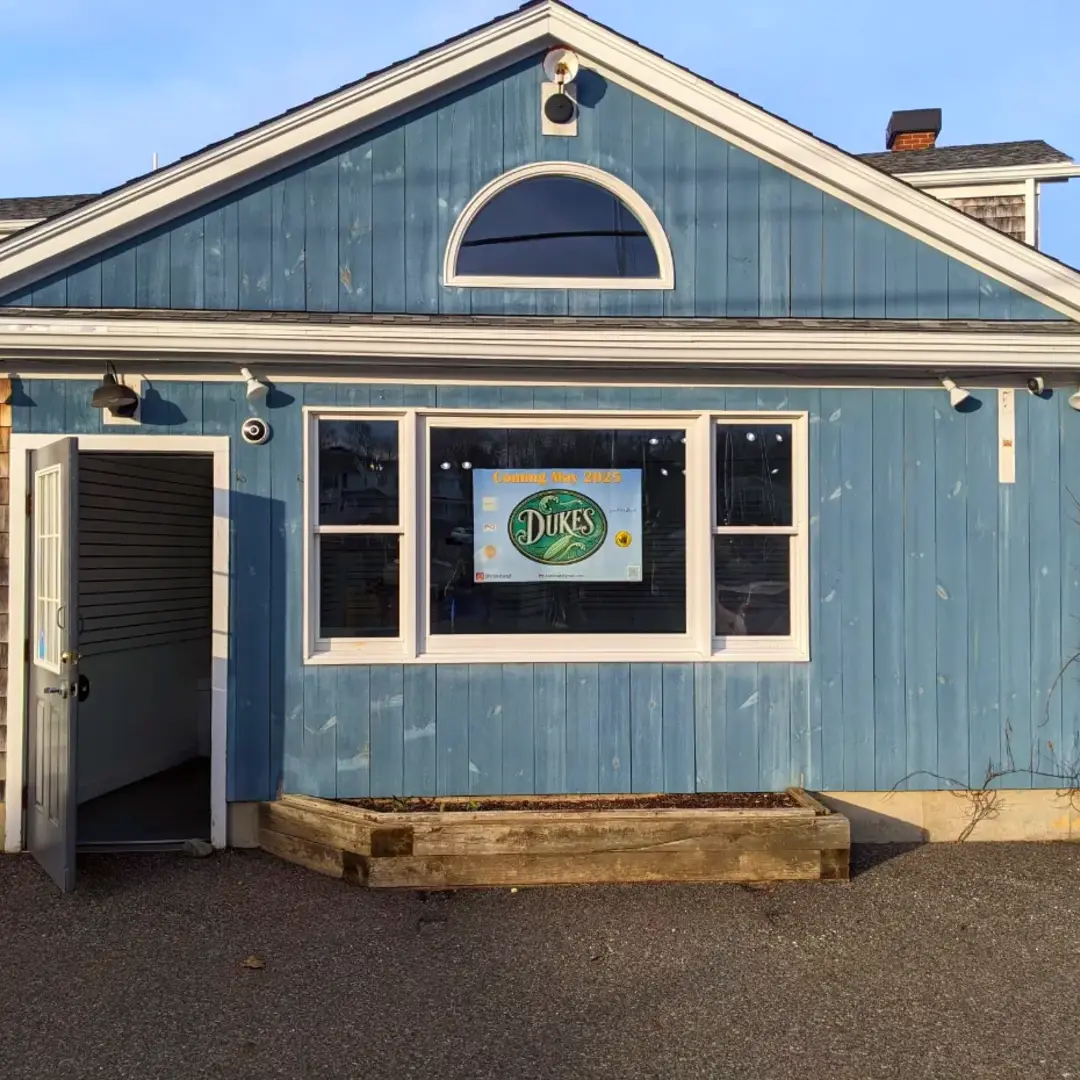 Front of a blue building with a sign that says 'Dukes'